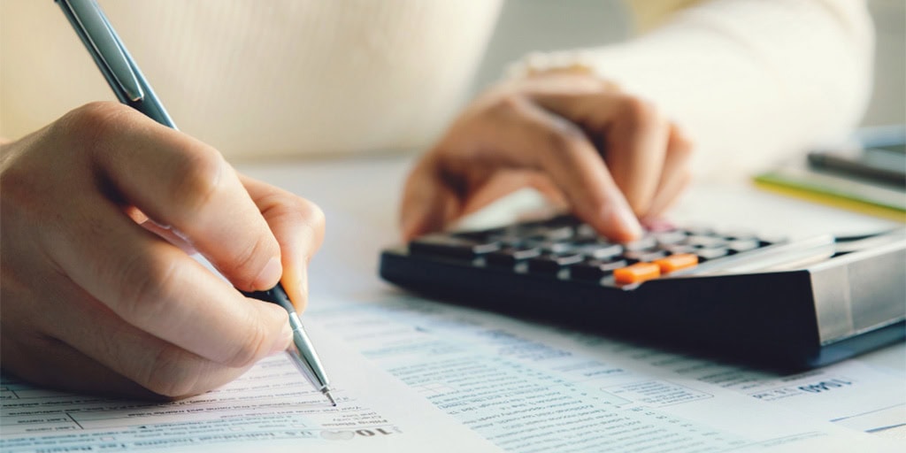 woman writing and using calculator